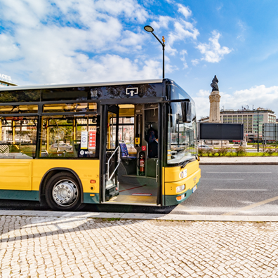 Fotografia da lateral de um autocarro parado junto ao Marquês de Pombal, em Lisboa, com a porta da frente aberta